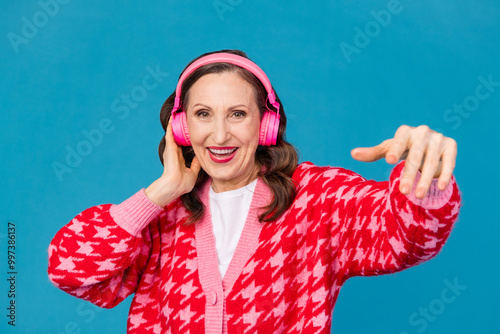 Photo portrait of nice pensioner female dance headphones listen music wear trendy pink print outfit isolated on blue color background photo