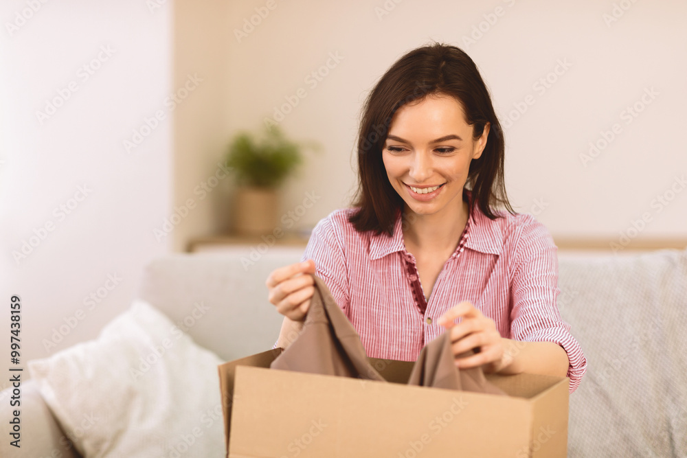 Donation Box. Happy woman putting clothes it in cardboard carton container with smiling facial expression, copyspace Donation Box. Happy woman putting clothes it in cardboard carton container with smiling facial expression, copyspace