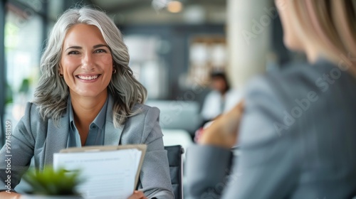 Fototapeta Naklejka Na Ścianę i Meble -  Smiling mature business woman hr holding cv document at job interview. Happy mid aged professional banking manager or lawyer consulting client sitting at workplace in corporate office meeting.