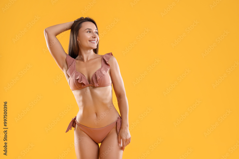 Woman in stylish bikini on orange background, space for text Woman in stylish bikini on orange background, space for text