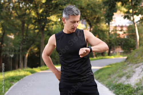 Man in sportswear checking time in park