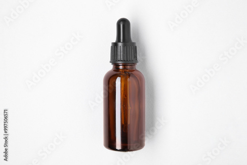 Essential oils in bottle on light background, top view