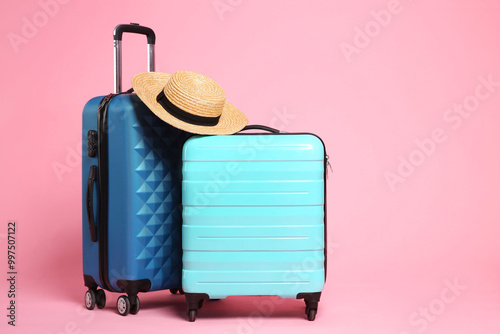 Two new color suitcases and wicker hat on pink background, space for text photo