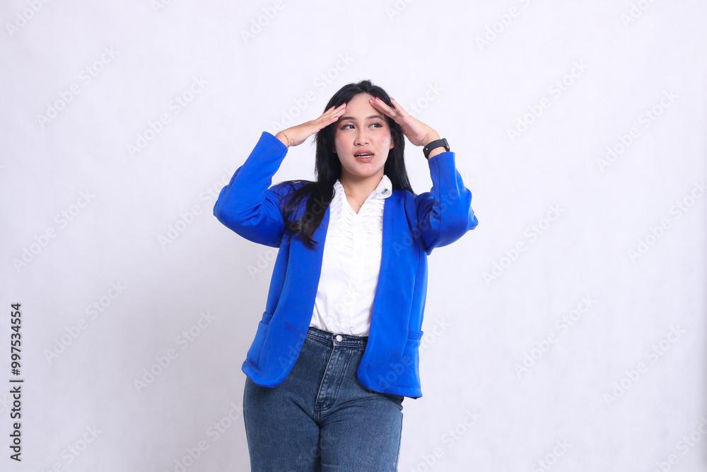 expression of beautiful young office woman wearing blue formal suit standing in front of camera screaming dizzy with both hands holding her head. for company, health, business, care, lifestyle content expression of beautiful young office woman wearing blue formal suit standing in front of camera screaming dizzy with both hands holding her head. for company, health, business, care, lifestyle content