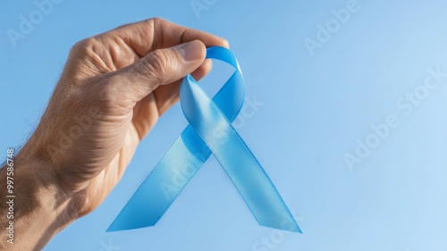 A hand holding a blue ribbon that says "breast cancer awareness"