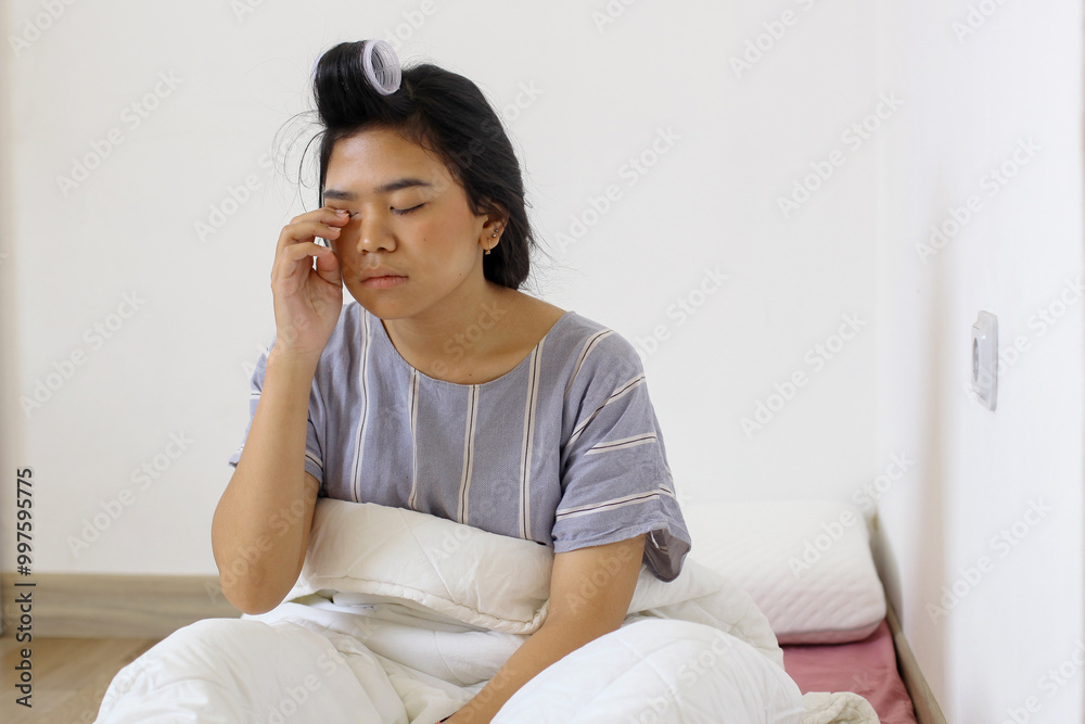 Asian woman rubbing eyes with her hands after waking up in the morning Asian woman rubbing eyes with her hands after waking up in the morning