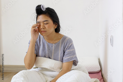 Asian woman rubbing eyes with her hands after waking up in the morning