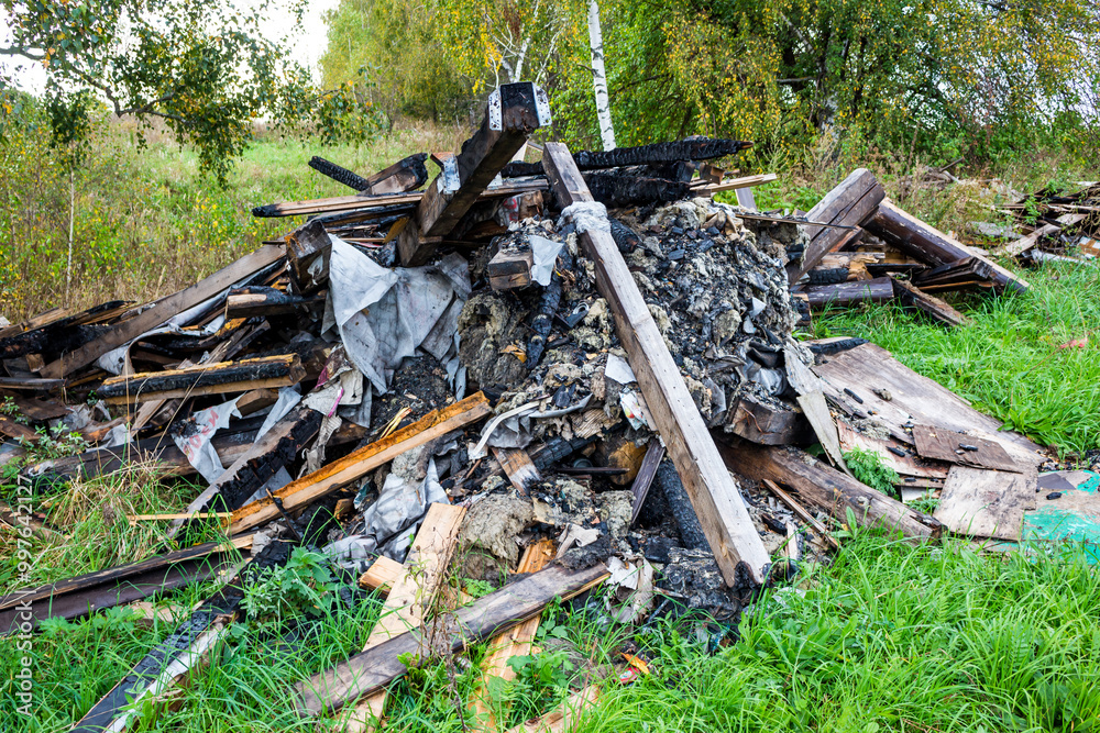 A pile of burnt garbage dumped in a field, illegal dump A pile of burnt garbage dumped in a field, illegal dump