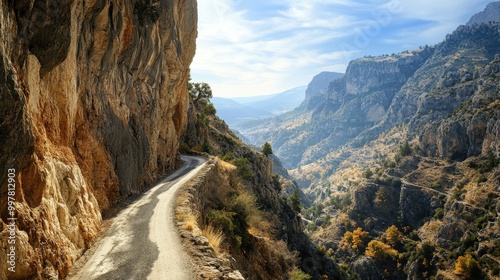 A narrow mountain road carved into the side of a cliff, with breathtaking views of the valley far below.