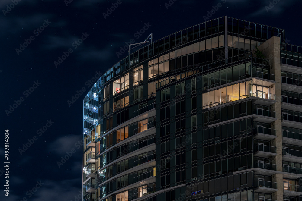 A skyscraper condo building set against a partially cloudy night sky with stars. A skyscraper condo building set against a partially cloudy night sky with stars.