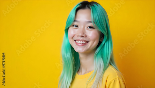 A young asian woman with long green dyed hair, smiling against a bright yellow background