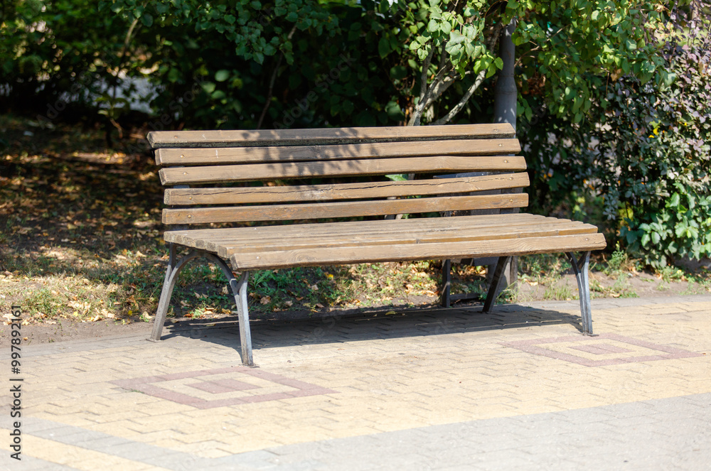 A wooden bench with a brown back and a white seat sits on a brick walkway A wooden bench with a brown back and a white seat sits on a brick walkway