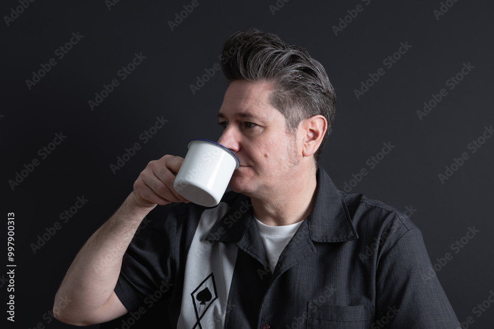 Mature man with nice hairstyle drinking a cup of coffee on dark background. Copy space. Concept of Concept of men, maturity and coffee Mature man with nice hairstyle drinking a cup of coffee on dark background. Copy space. Concept of Concept of men, maturity and coffee