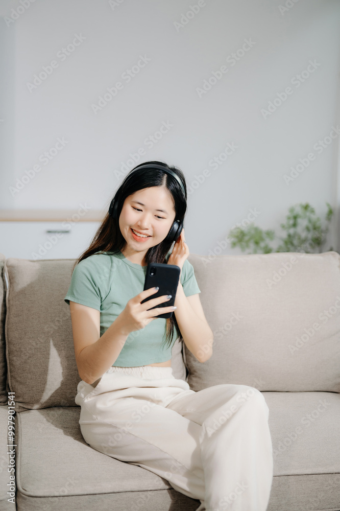 Young asian woman relax on comfortable couch at home texting messaging on smartphone and tablet smiling girl use cellphone shopping online Young asian woman relax on comfortable couch at home texting messaging on smartphone and tablet smiling girl use cellphone shopping online