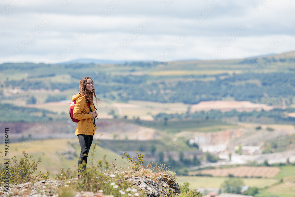 Naklejka premium Young woman enjoying nature.Hiking in the mountains, observing the landscape.Doing sports and physical activity.Let's take care of our natural surroundings and our environment.Moments of disconnection