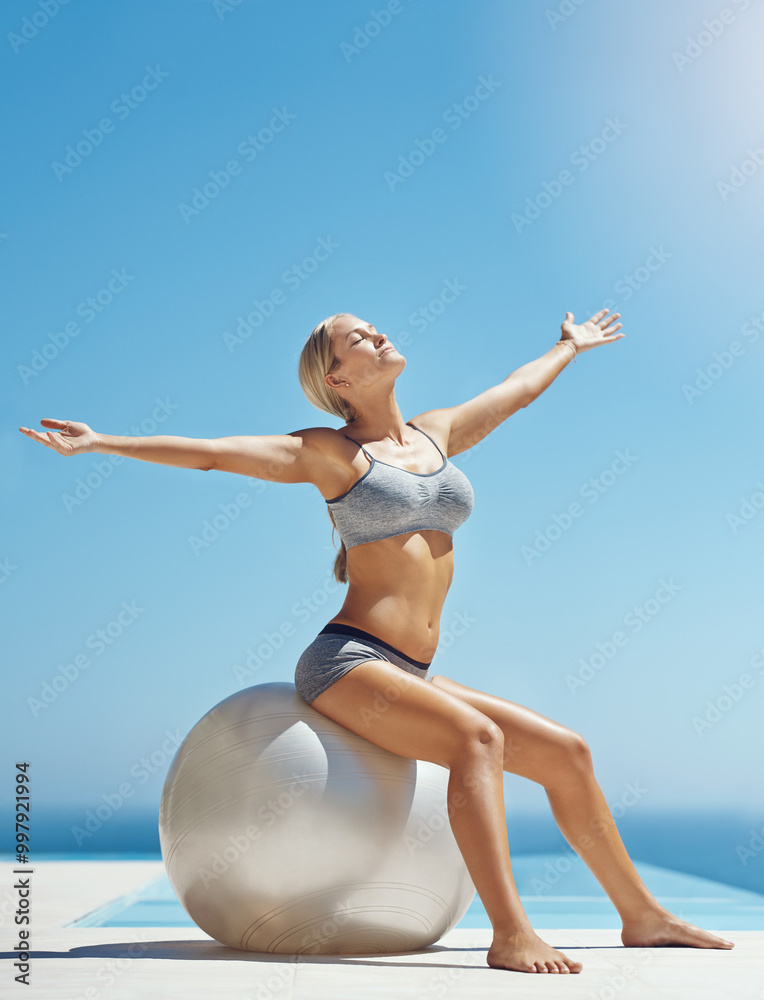 Fototapeta premium Woman, yoga and zen with exercise ball for workout, fitness or outdoor training by swimming pool. Young, female person or stretching with blue sky for warm up, balance or pilates in sunshine on space