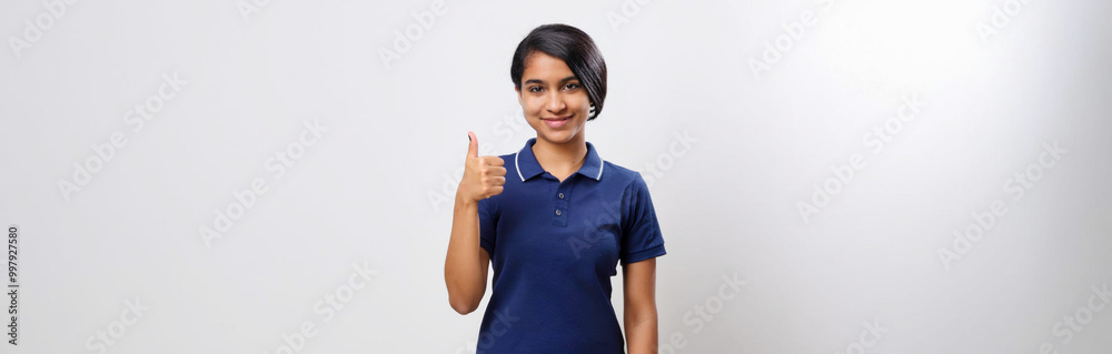 A portrait of an Asian woman wearing a navy polo shirt, smiling and giving a thumbs-up against a white background. A portrait of an Asian woman wearing a navy polo shirt, smiling and giving a thumbs-up against a white background.