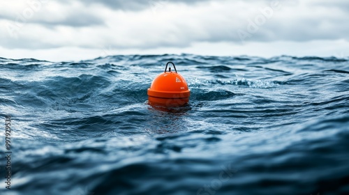 A bright orange buoy floats on the vast, turbulent ocean under a cloudy sky, symbolizing navigation and maritime safety.