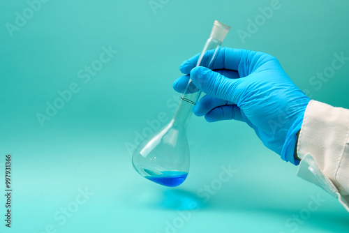 hand with volumetric flask that has a blue chemical liquid.