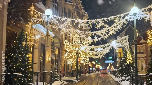 Blurred christmass background. Snow-covered city street with festive lights bokeh and buildings adorned for the holiday season.