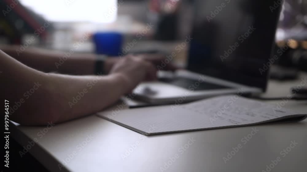 Man Working on Laptop and Taking Notes in Notebook