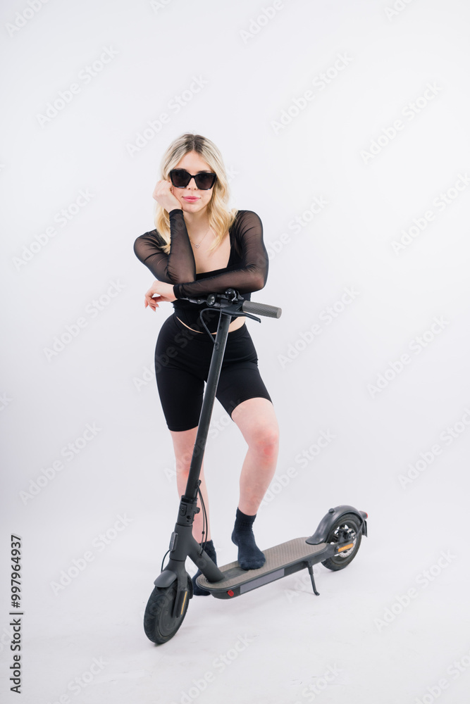 Fototapeta premium Woman ride e-scooter looking camera isolated on white background studio portrait. Lifestyle concept