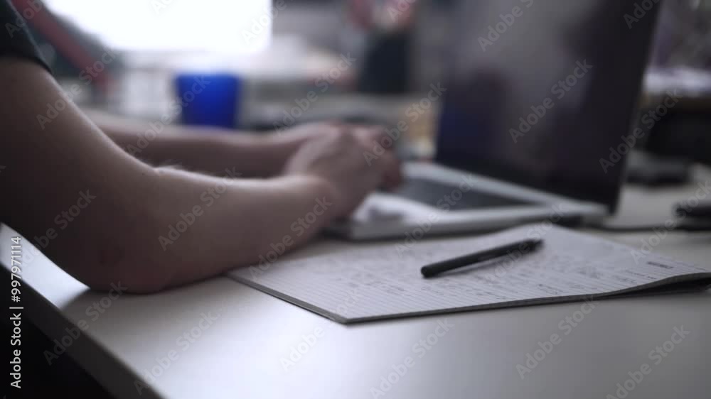 Man Working on Laptop and Taking Notes in Notebook Man Working on Laptop and Taking Notes in Notebook