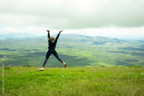 A young black woman frolicking in the grass in the hills after a hike photo