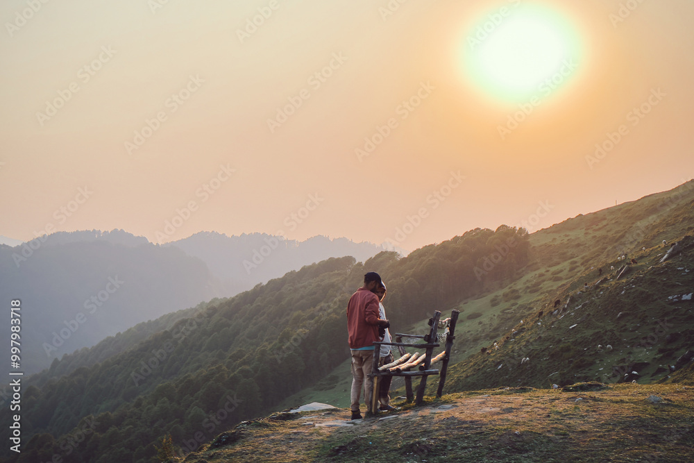 Two men sitting on a bench chairs enjoy sunset and chatting outdoors at the Top of Raghupur Fort - Tirthan Valley Himanchal pradesh india. Two men sitting on a bench chairs enjoy sunset and chatting outdoors at the Top of Raghupur Fort - Tirthan Valley Himanchal pradesh india.