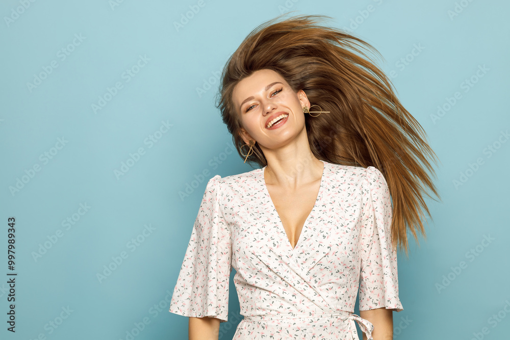 Obraz premium Young woman waving her hair in a dress on a blue background.