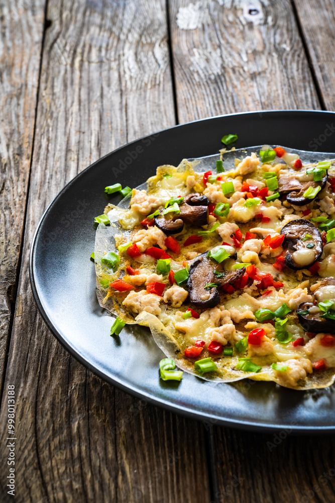 Vietnamese pizza - rice pepper omelet with mushrooms chicken meat and fresh vegetables served on black plate on wooden table
Vietnamese pizza - rice pepper omelet with mushrooms chicken meat and fresh vegetables served on black plate on wooden table