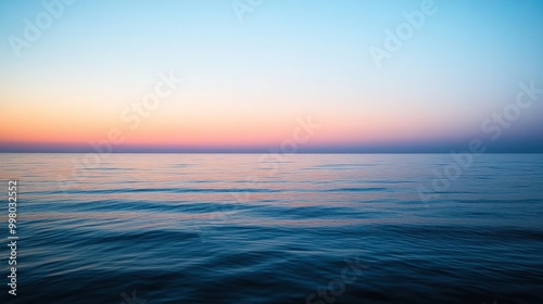 A tranquil view of the ocean at sunset, with a colorful sky reflected in the water.