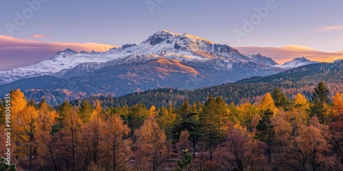 Warm Sunrise Glow on a Snow-Capped Peak with Autumn Forest Below