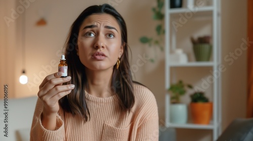 Woman holding small bottle of weight-loss pills, looking determined and focused in a minimalist, well-lit room with copy space for text. photo