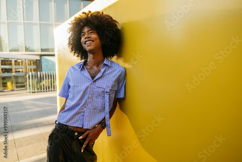 Smiling gay man day dreaming near yellow wall