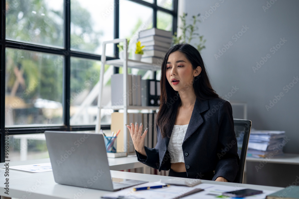 A woman is sitting at a desk with a laptop in front of her A woman is sitting at a desk with a laptop in front of her