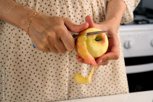 Woman peeling apple using knife cooking food dish on kitchen at home, hands close-up. Female housewife in dress preparing dish from apples. Culinary, cuisine, healthy eating, baking concept. photo