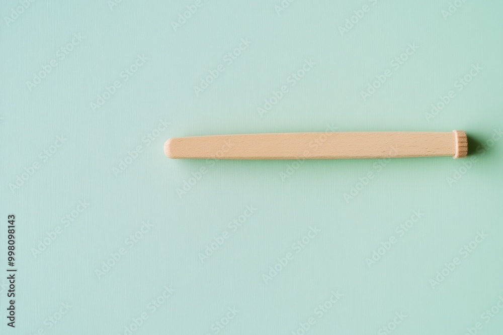 Simple wooden stick placed on a soft blue green background showcasing minimalist aesthetics in design Simple wooden stick placed on a soft blue green background showcasing minimalist aesthetics in design