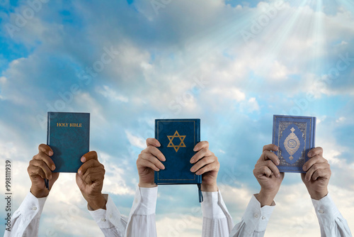 Photography Hands holding Quran, Bible, Talmud or Torah against the sky