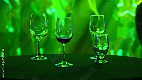 Wine Alcohol Glasses Left Unattended on Table at Disco Club by Dance Floor with People Dancing and Having Fun photo