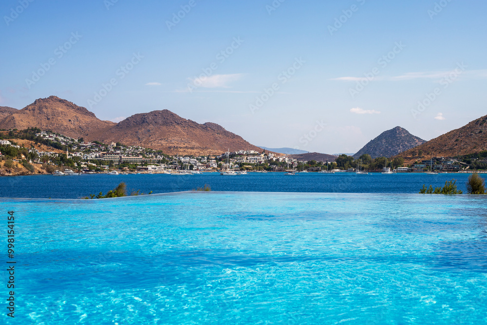 Obraz premium Magnificent view of turquoise water pool and dark blue Aegean sea near luxury Turkish hotel in Akyarlar area of ​​Bodrum province, Turkey.