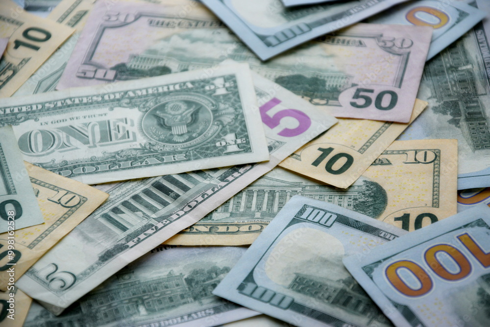 Big amount of US dollar bills in different nominations on table. Many dollar banknotes under natural light Big amount of US dollar bills in different nominations on table. Many dollar banknotes under natural light