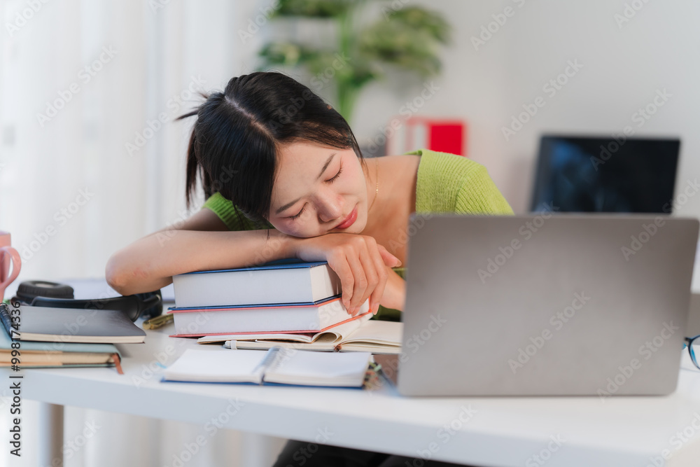 Student Exhaustion: Young woman asleep on desk with laptop and books. Student Exhaustion: Young woman asleep on desk with laptop and books.