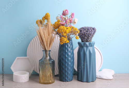 Vases with dry flowers and plaster shapers on a blue background. Minimalistic still life