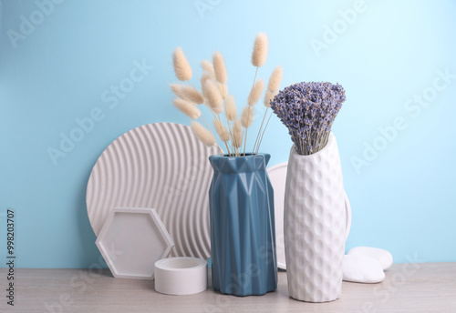 Vases with dry lagurus and lavender flowers and plaster shapers on a blue background. Minimalistic still life photo