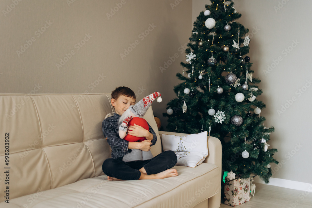 boy sitting with a toy in his hands against the background of a Christmas tree boy sitting with a toy in his hands against the background of a Christmas tree