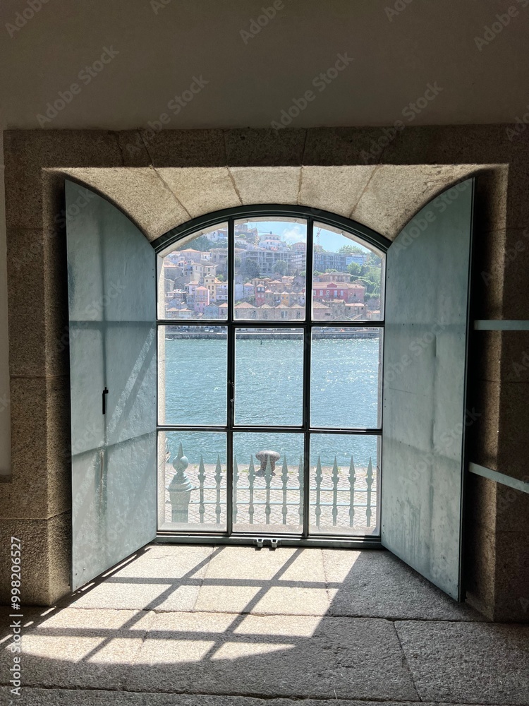 A serene glimpse of the Douro River at sunset, viewed through a window with light filtering in, casting a warm glow on the interior of a traditional building in Porto's port district. A serene glimpse of the Douro River at sunset, viewed through a window with light filtering in, casting a warm glow on the interior of a traditional building in Porto's port district.