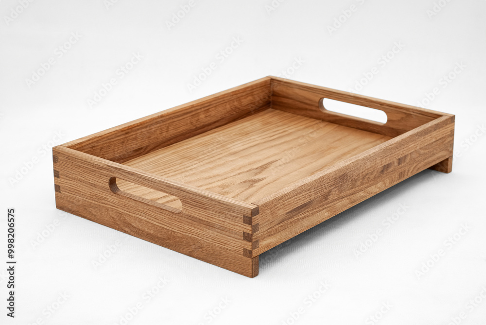 Solid oak wood tray with dovetail joints and cutout handles on the sides for easy carrying on white background Solid oak wood tray with dovetail joints and cutout handles on the sides for easy carrying on white background