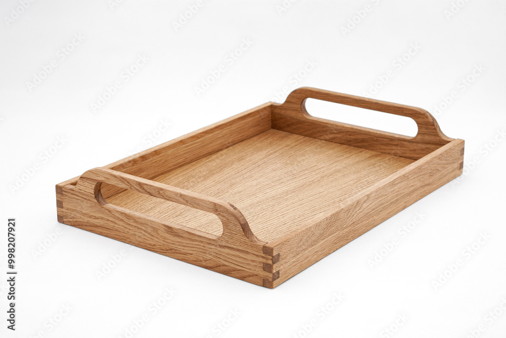 Elegant solid oak wood tray with dovetail joints and carved handles on the sides for easy carrying on white background Elegant solid oak wood tray with dovetail joints and carved handles on the sides for easy carrying on white background
