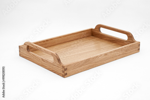 Elegant solid oak wood tray with dovetail joints and carved handles on the sides for easy carrying on white background photo